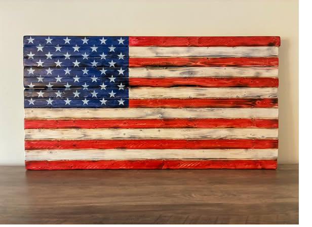 Handcrafted wood American flag with vibrant hand-stained red and white stripes and stenciled spray-painted stars, displayed as patriotic wall decor