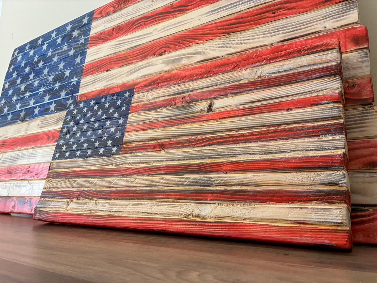 Angled close-up of a handcrafted wood American flag showing the raised three-dimensional pine stripes and natural wood grain