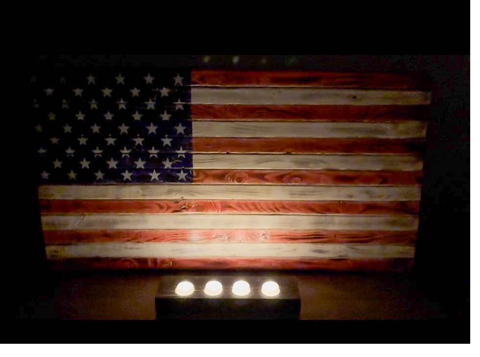 Rustic wood American flag glowing in candlelight as patriotic home wall decor and a meaningful veteran gift