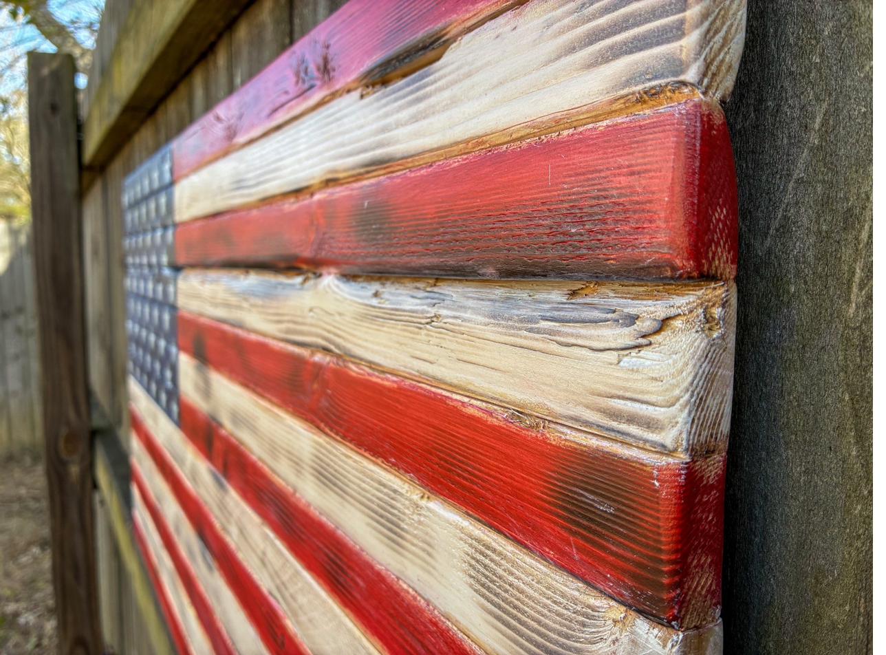 Weathered rustic wood American flag photographed against a fence outdoors, a handmade patriotic gift